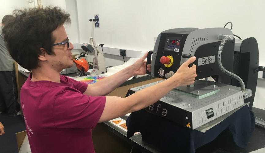 Matt operating the t-shirt printing press at Aspire